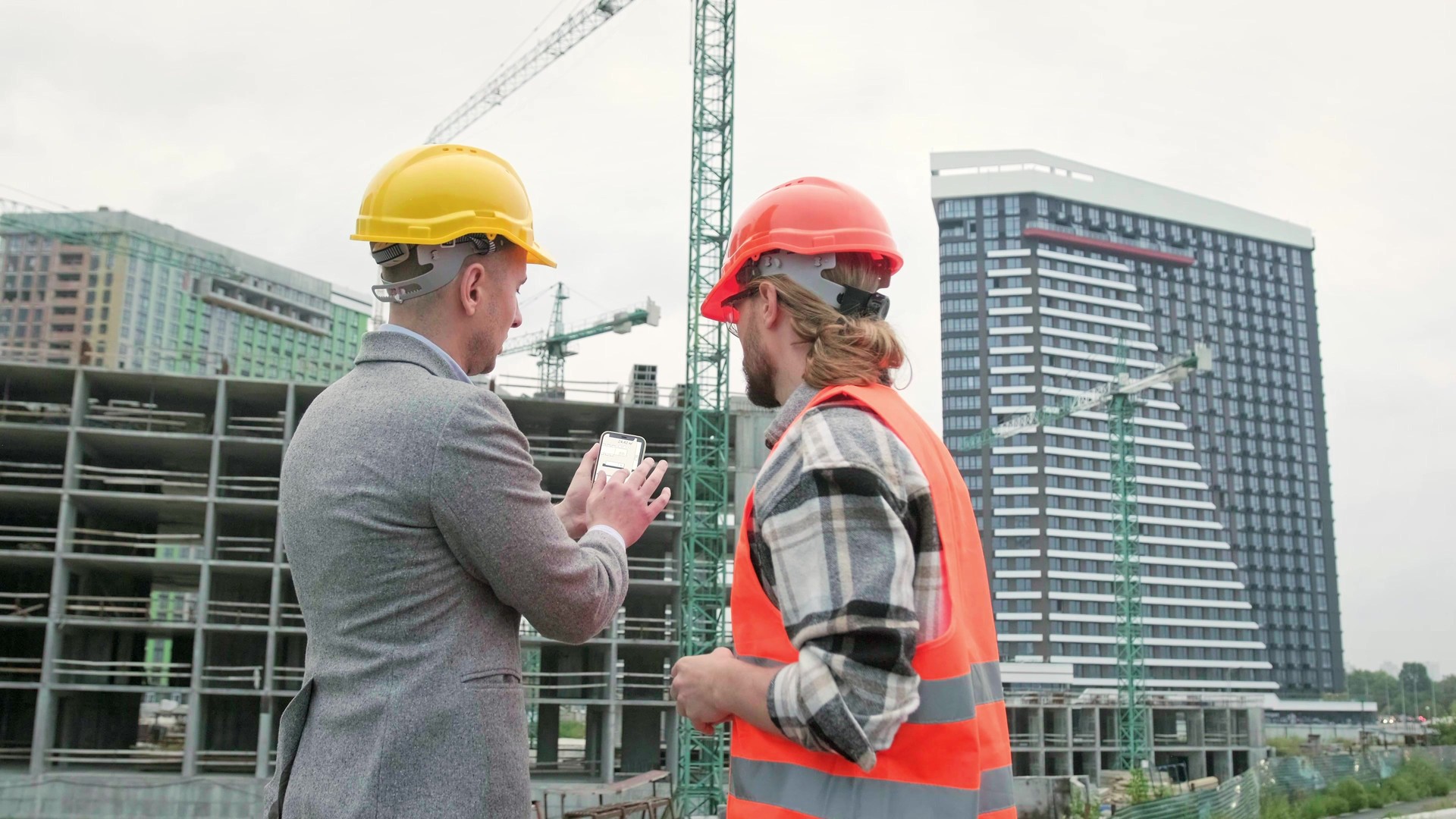 General contractor and subcontractor using smartphone during site inspection